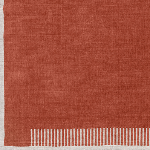 Close-up of the Duomo Rug in Terracotta Red, showing the corner with its woven texture and striped off-white border.