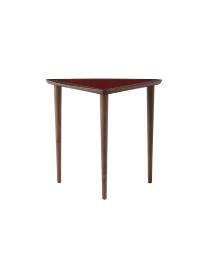 A front view of the triangular Umanoff Nesting Side Table, featuring a walnut frame, three tapered legs, and a burgundy top.