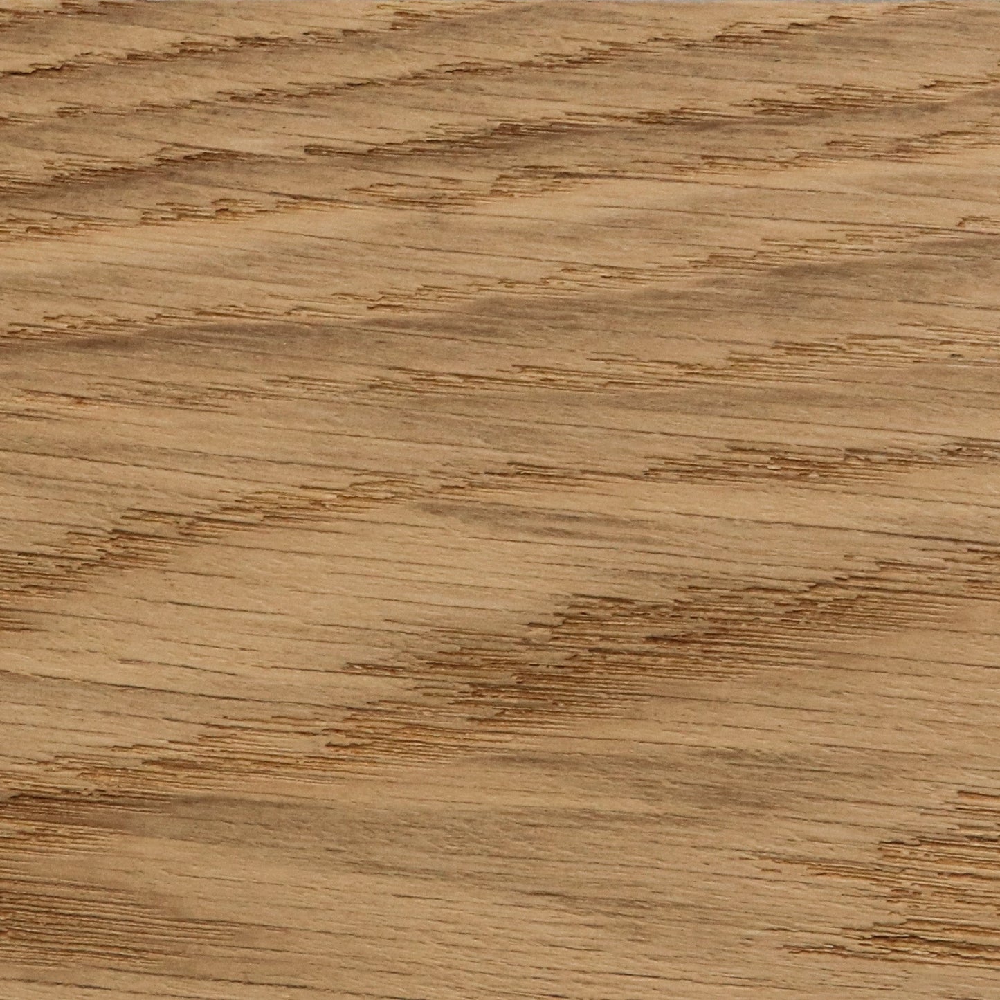 A detailed close-up of a golden oak wood finish, showing the distinct texture and diagonal lines of the natural wood grain.