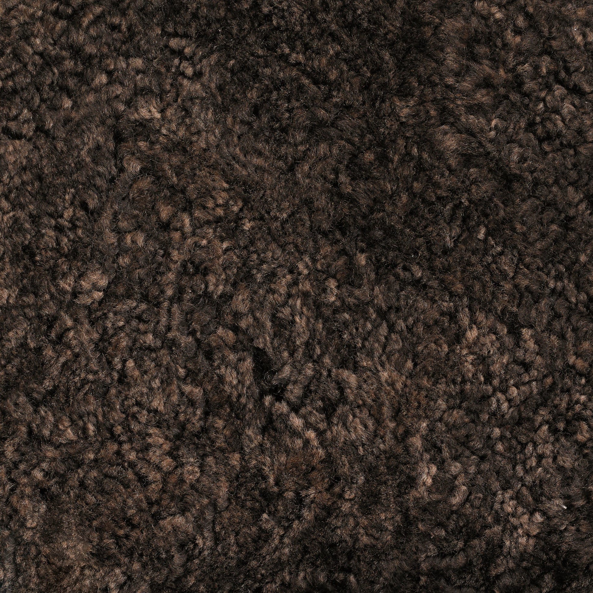 A close-up texture shot of Skandilock Sheepskin in the colour Espresso. The dark brown wool is thick, soft, and curly.