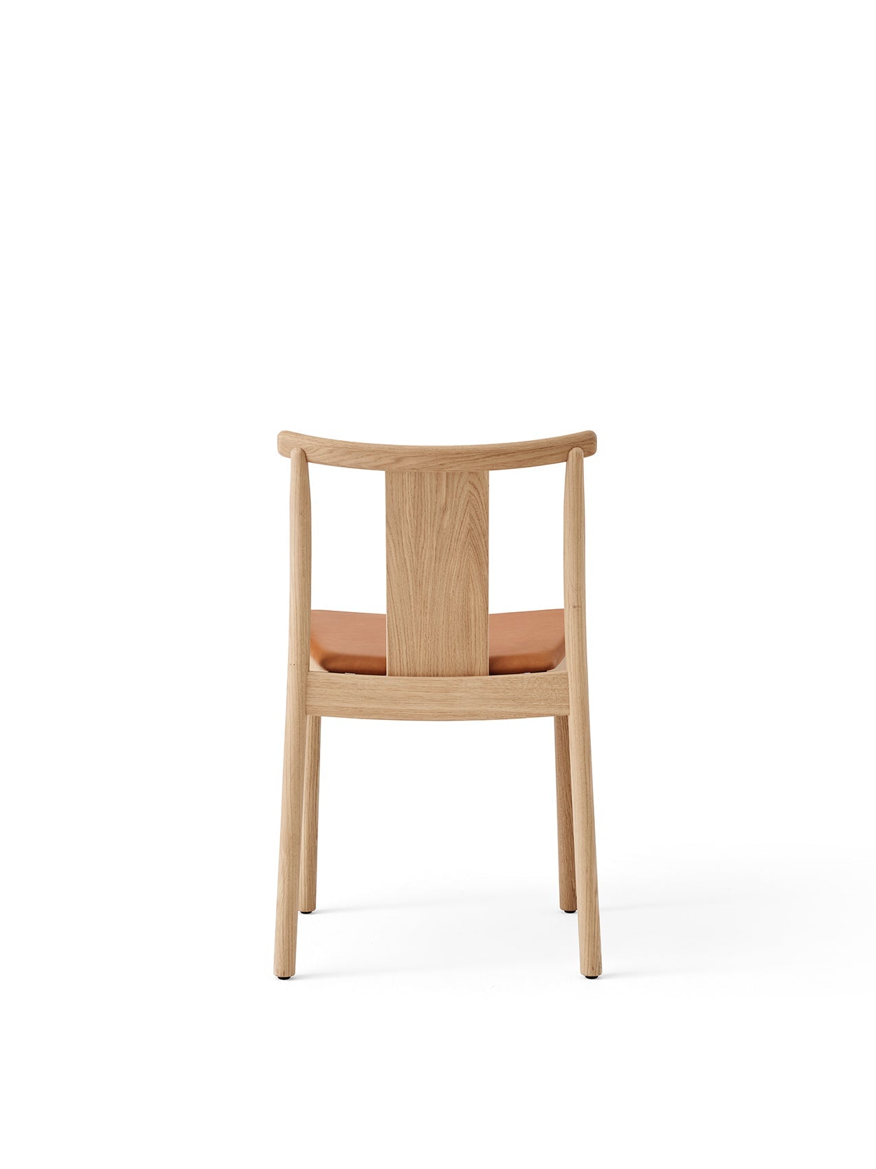 Rear view of the Merkur Dining Chair in natural oak. It has a curved backrest and a padded seat upholstered in tan leather.