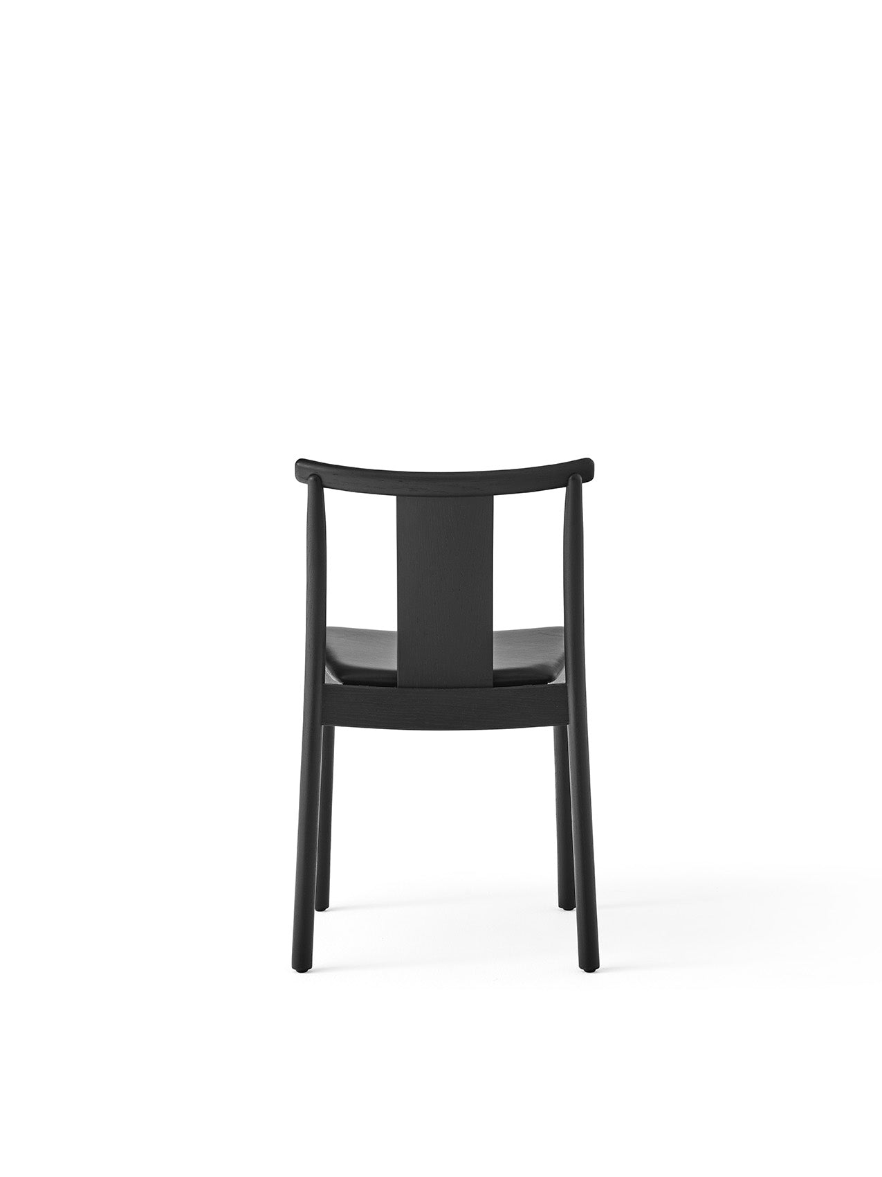 Back view of the Merkur Dining Chair in black oak, showing its curved top rail, wide central back splat, and slim legs.