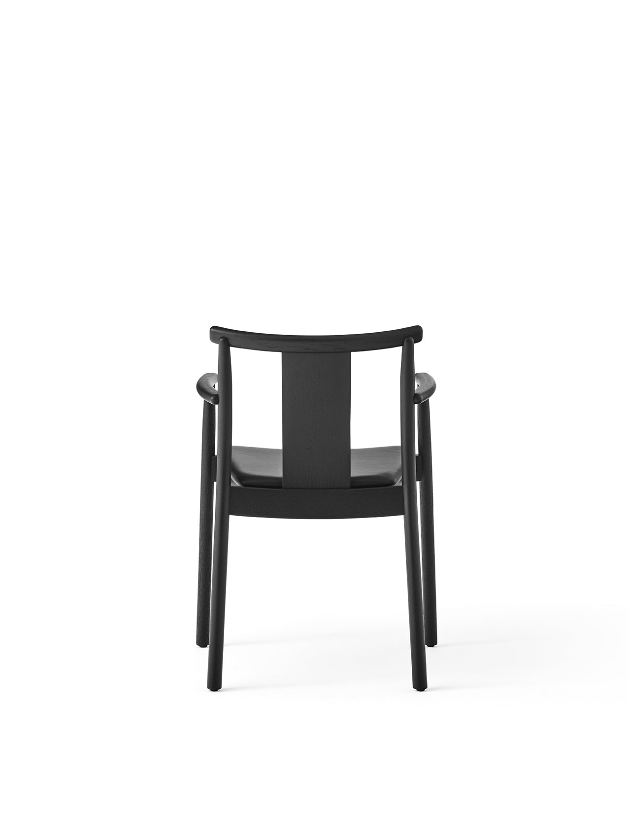 The Merkur Dining Chair with Armrests in black stained oak with a black leather seat, viewed from the back.