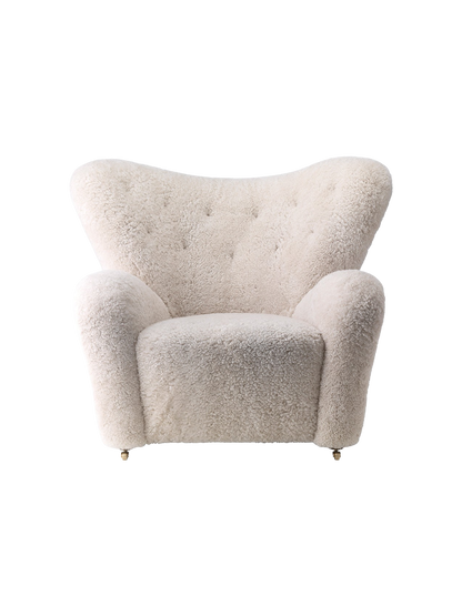 Front view of The Tired Man Lounge Chair upholstered in plush, off-white sheepskin, with a high, curved, button-tufted back.