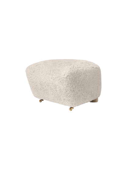 The Tired Man Ottoman in soft, off-white Moonlight sheepskin. The plush footstool features oak legs with brass castors.