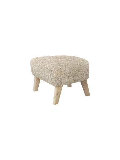 High-angle view of the My Own Chair, Ottoman. It has a rounded triangular seat upholstered in off-white Sheepskin Moonlight.