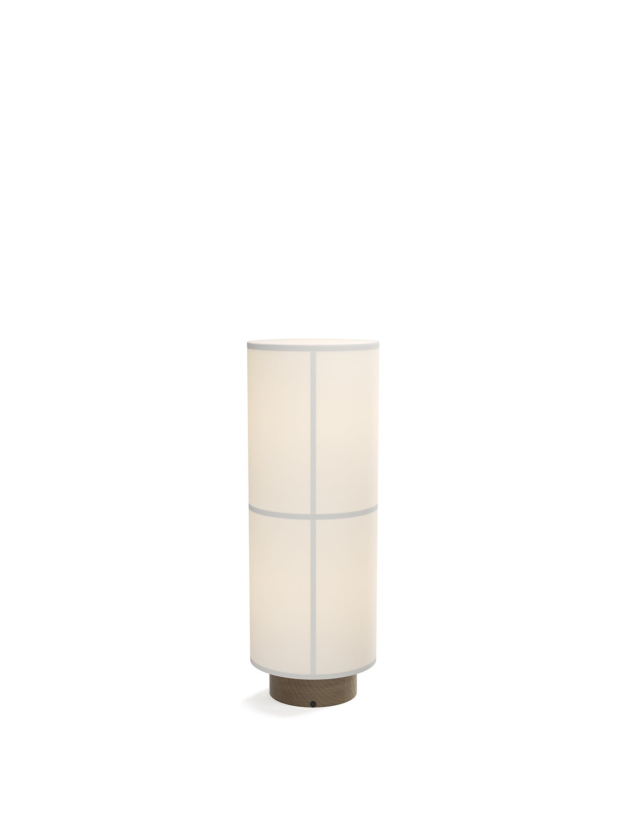 The white Hashira Floor Lamp is illuminated against a dark background, with a cylindrical linen shade on a wooden base.