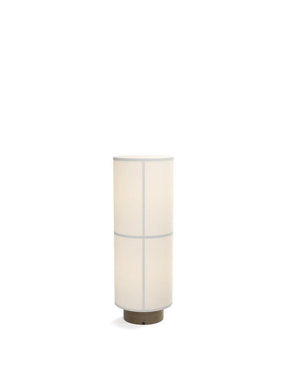 The white Hashira Floor Lamp is illuminated against a dark background, with a cylindrical linen shade on a wooden base.