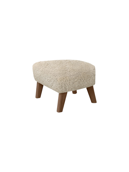 A My Own Chair, Ottoman with a fluffy, off-white Sheepskin Moonlight seat and four angled wooden legs, on a black background.