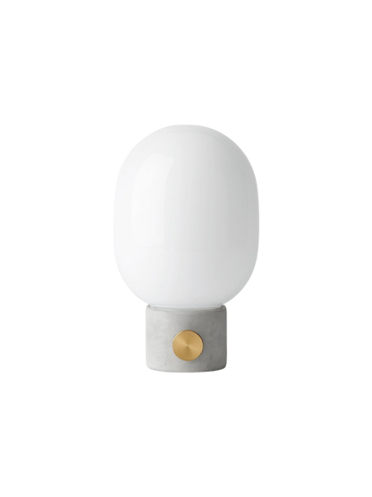 Front view of the JWDA Table Lamp in light grey concrete, with a brass dimmer knob and a rounded white opal glass shade.