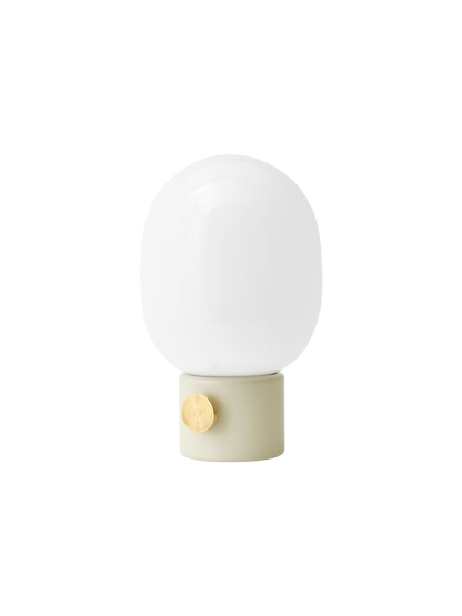 Angled view of the JWDA Table Lamp, Small, in Alabaster White steel with a brass dimmer and a rounded opal glass shade.