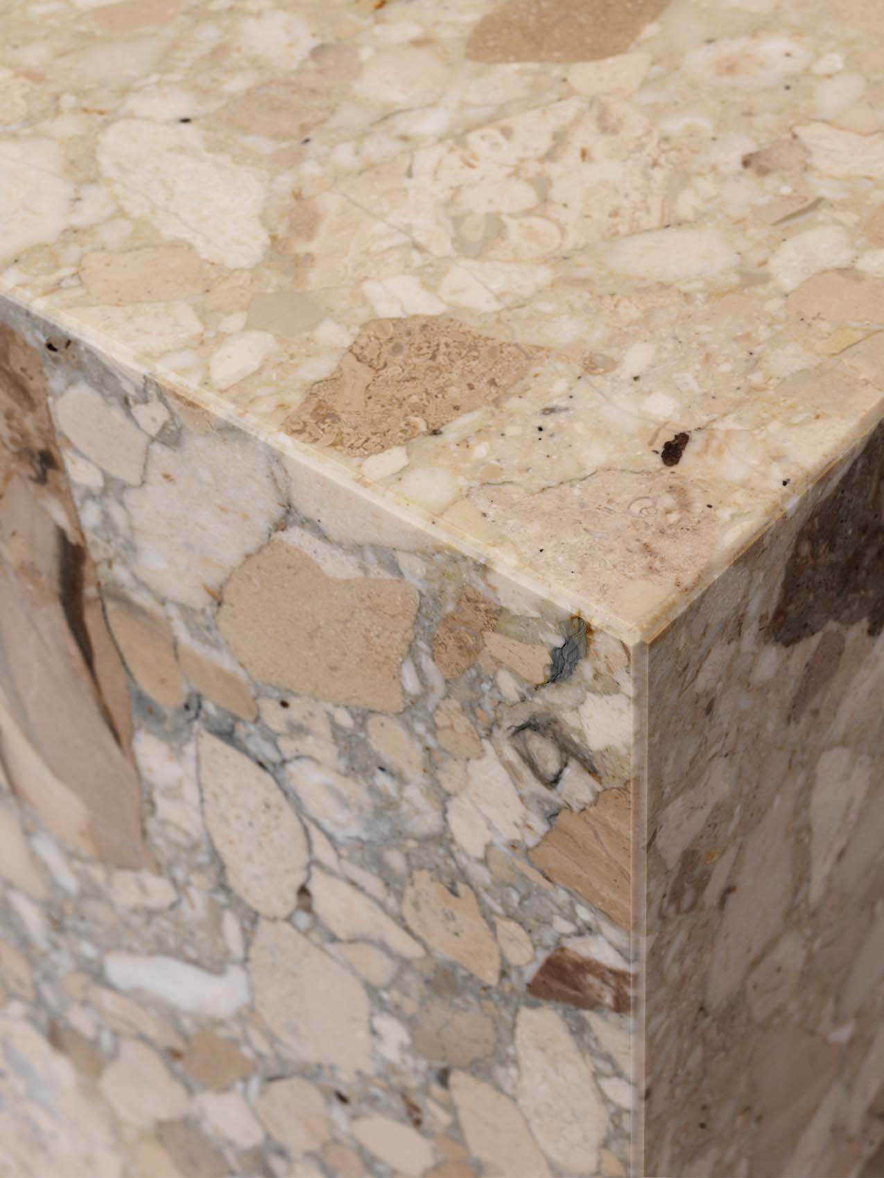 Close-up corner of the Plinth Grand, showing the Kunis Breccia marble's detailed pattern of beige and grey tones.