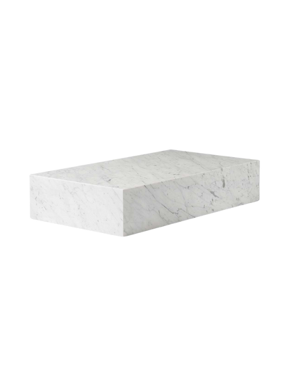 Angled view of the Plinth Grand, a low rectangular table made of white Carrara marble with subtle grey veining.