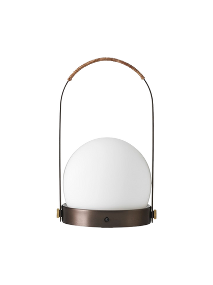 Front view of the Carrie Table Lamp in bronzed brass, featuring a white opal glass orb and a handle wrapped in brown leather.