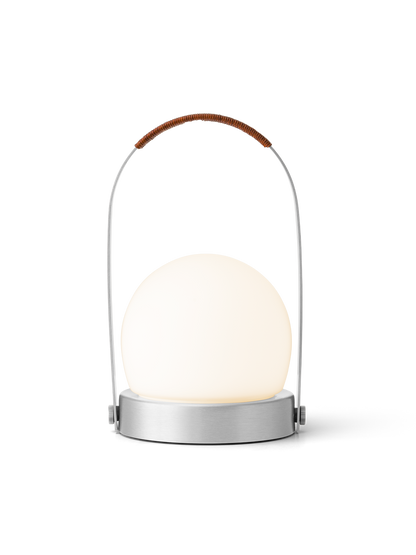 Carrie Portable Lamp with a brushed aluminium base, glowing opal glass shade and brown leather-wrapped handle.