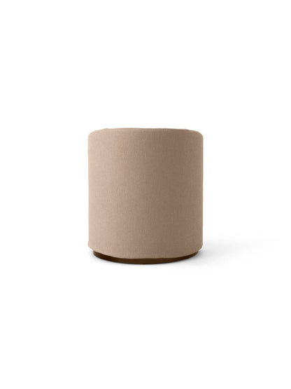 Front view of the cylindrical Tearoom pouf, upholstered in textured beige Logan Flint fabric, with a dark recessed base.