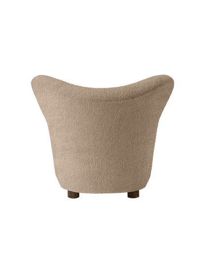 Back view of The Tired Man Lounge Chair upholstered in a textured beige textile, showing its curved back and dark oak legs.