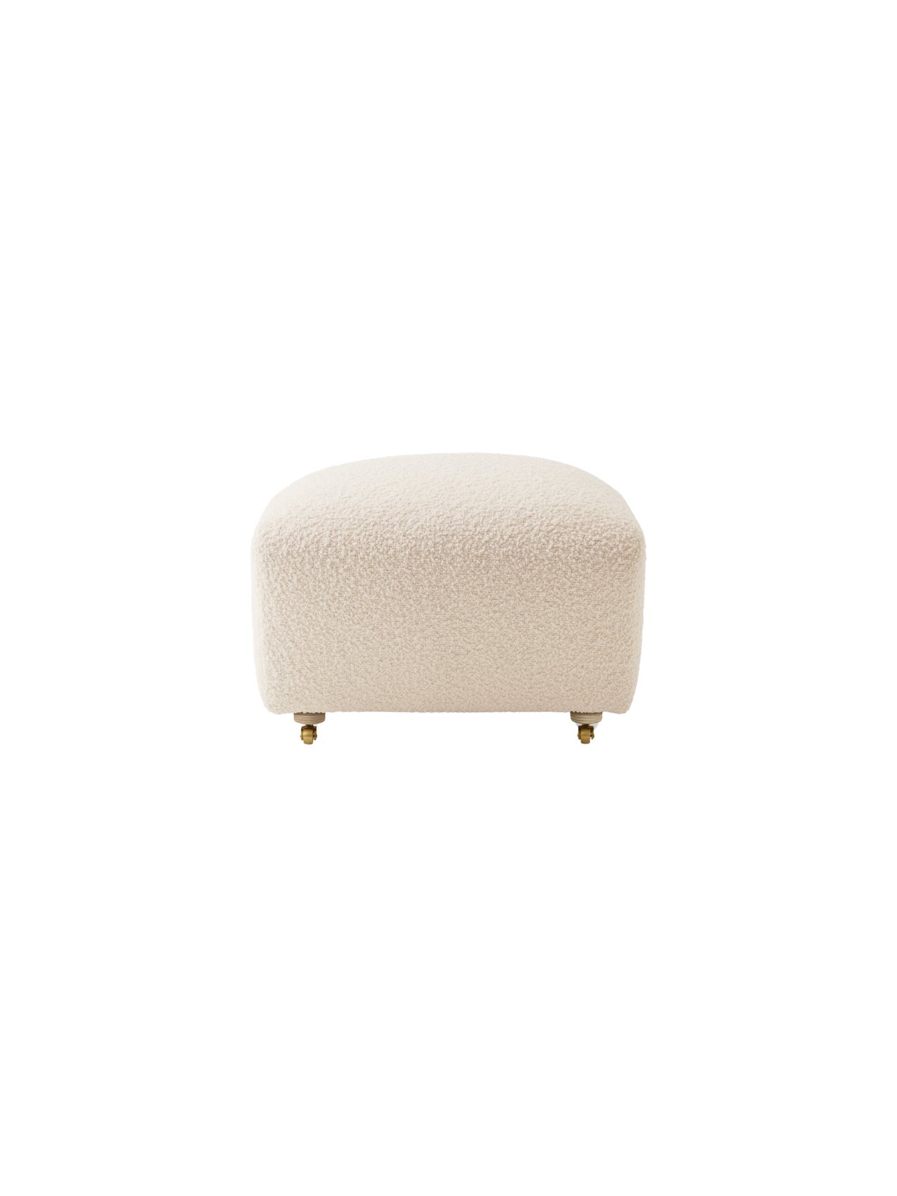 A front view of The Tired Man Ottoman, upholstered in a plush, off-white textile, with light oak legs and brass casters.