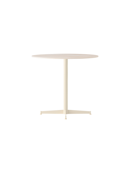 Angle view of the Nook Dining Table, featuring a round Estremoz Marble top and an ivory powder-coated steel four-star base.