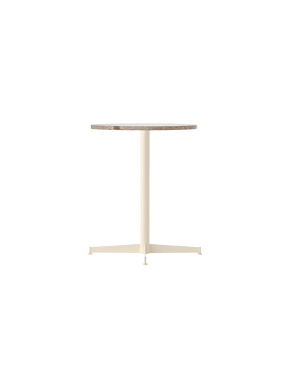 An angled view of the Nook Dining Table with a round Kunis Breccia stone top and a slim, four-star base in ivory.