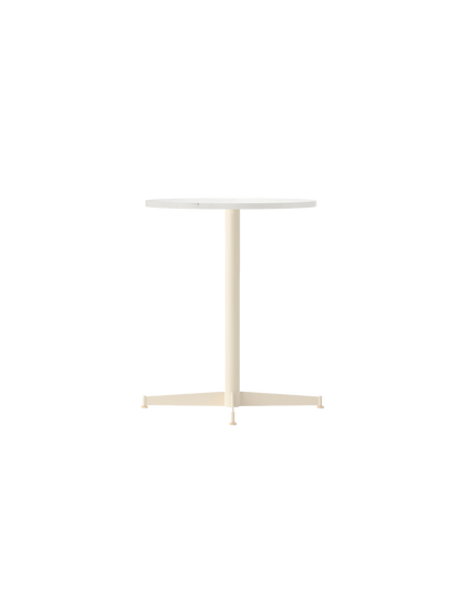 An angled view of the Nook Dining Table with a round Estremoz marble top and an ivory powder-coated steel four-star base.