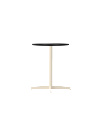 Angle view of the Nook Dining Table with a round charcoal linoleum top and a slim, ivory powder-coated steel four-star base.