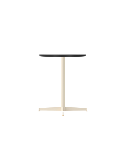 The Nook Dining Table, shown at an angle, featuring a circular black oak veneer top and a slim, four-star base in ivory.