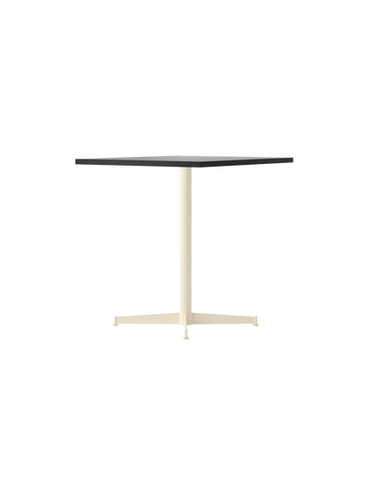 Angled view of the Nook Dining Table with a square charcoal linoleum top and a slim, ivory-coloured, four-star steel base.