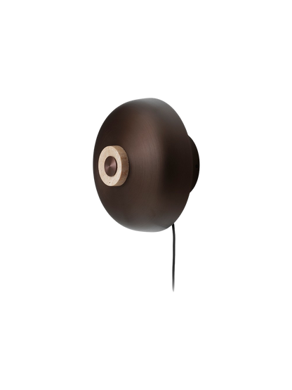 An angled shot of the Reverse Wall Lamp on a black background, showing its bronzed aluminium shade and travertine dimmer.