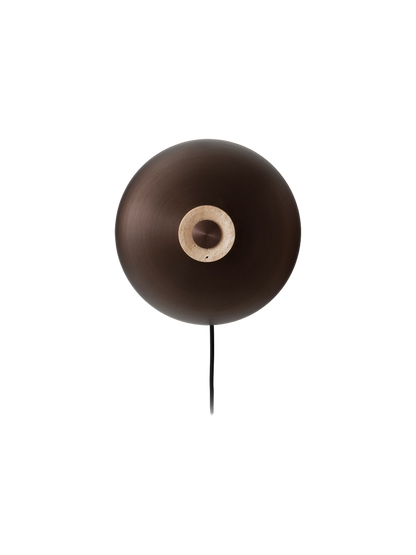 A front view of the Reverse Wall Lamp, with a circular bronzed aluminium shade and a central travertine base with a dimmer.