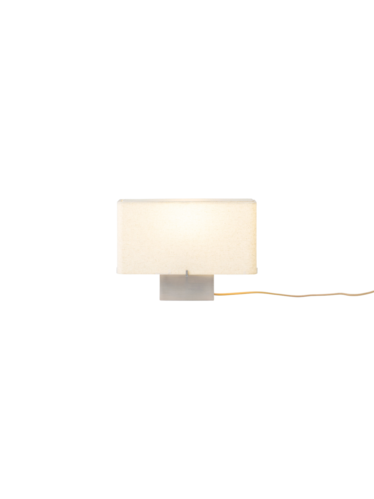 Front view of the illuminated Nonna Table Lamp with its rectangular, sand-coloured shade and brushed aluminium base.
