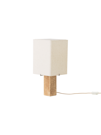 Angled view of the Nonna Table Lamp, off. It features a rectangular travertine base and a square, sand-hued shade.