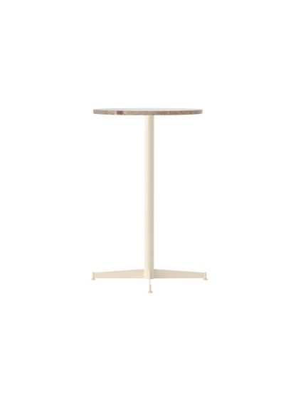 The Nook Counter Table shown at an angle, featuring a round Kunis Breccia stone top and a slim, ivory-coloured metal base.