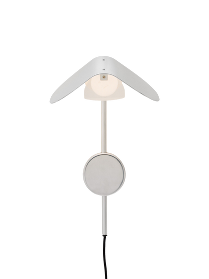 A front view of the illuminated Wing Wall Lamp in polished aluminium, featuring a wing-like shade over a glowing diffuser.