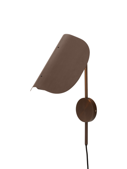 Angled view of the bronzed aluminium Wing Wall Lamp with its light on, highlighting the distinctive wing-shaped shade.