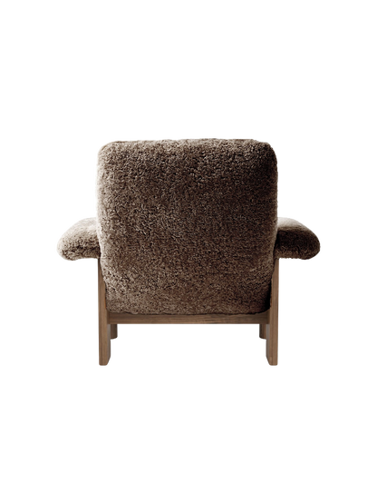 Rear view of the Brasilia Lounge Chair, High Back, in brown sheepskin with a dark walnut frame on a black background.