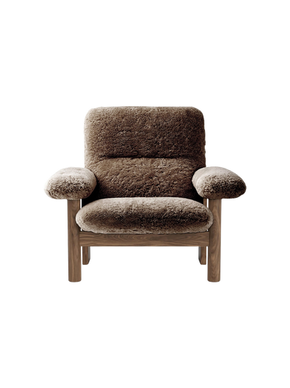The Brasilia Lounge Chair, High Back, shown front-on. It has a dark wood frame and is upholstered in plush, brown sheepskin.