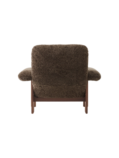 Back view of the Brasilia Lounge Chair, upholstered in fluffy dark brown Sheepskin Root with a dark walnut wood frame.