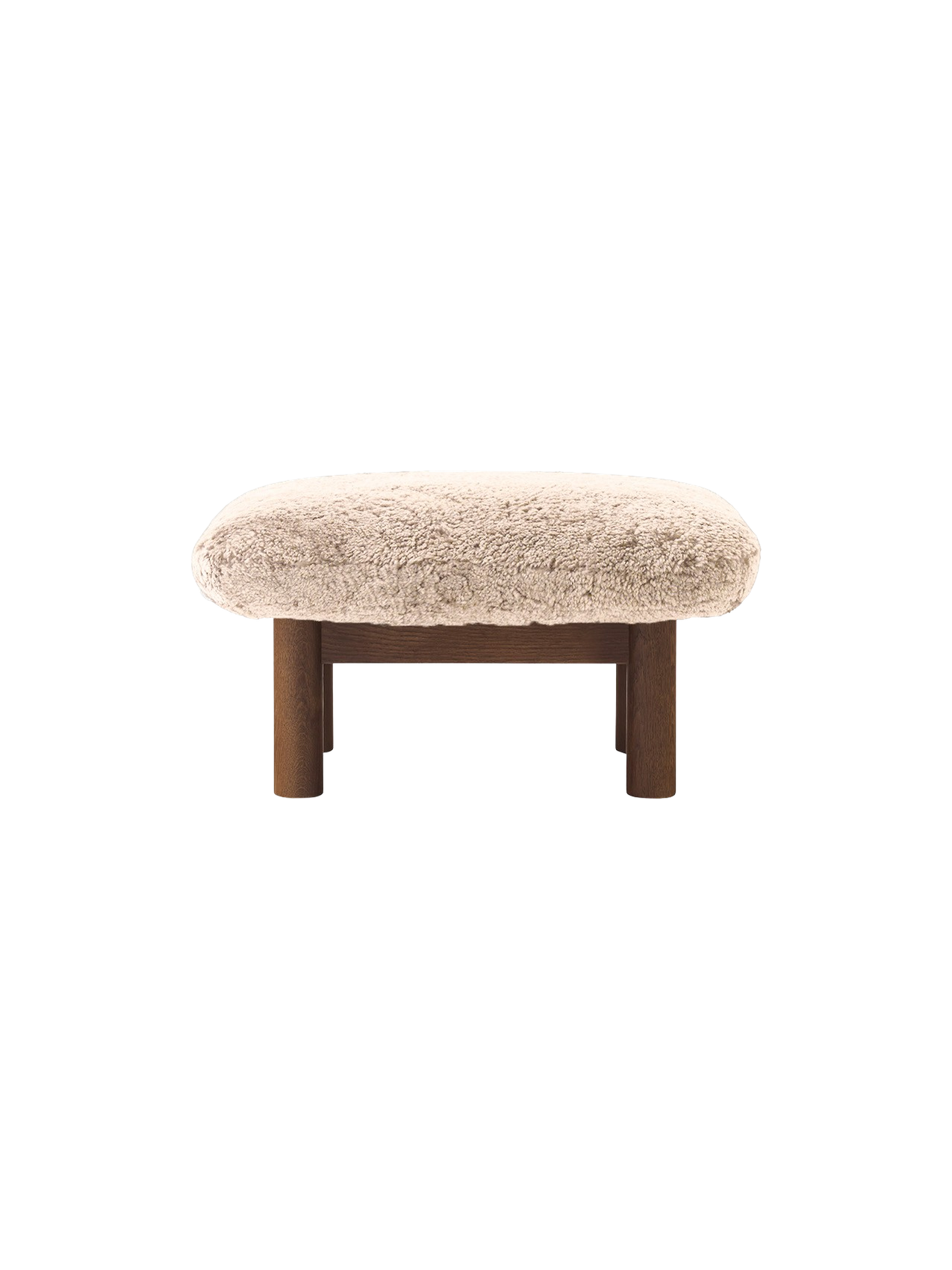 The Brasilia Ottoman with a plush Sheepskin Root cushion on a dark-stained oak frame and four robust legs.