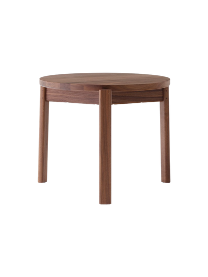 A Passage Lounge Table in dark walnut wood, shown from the front on a black background, with a round top and three legs.