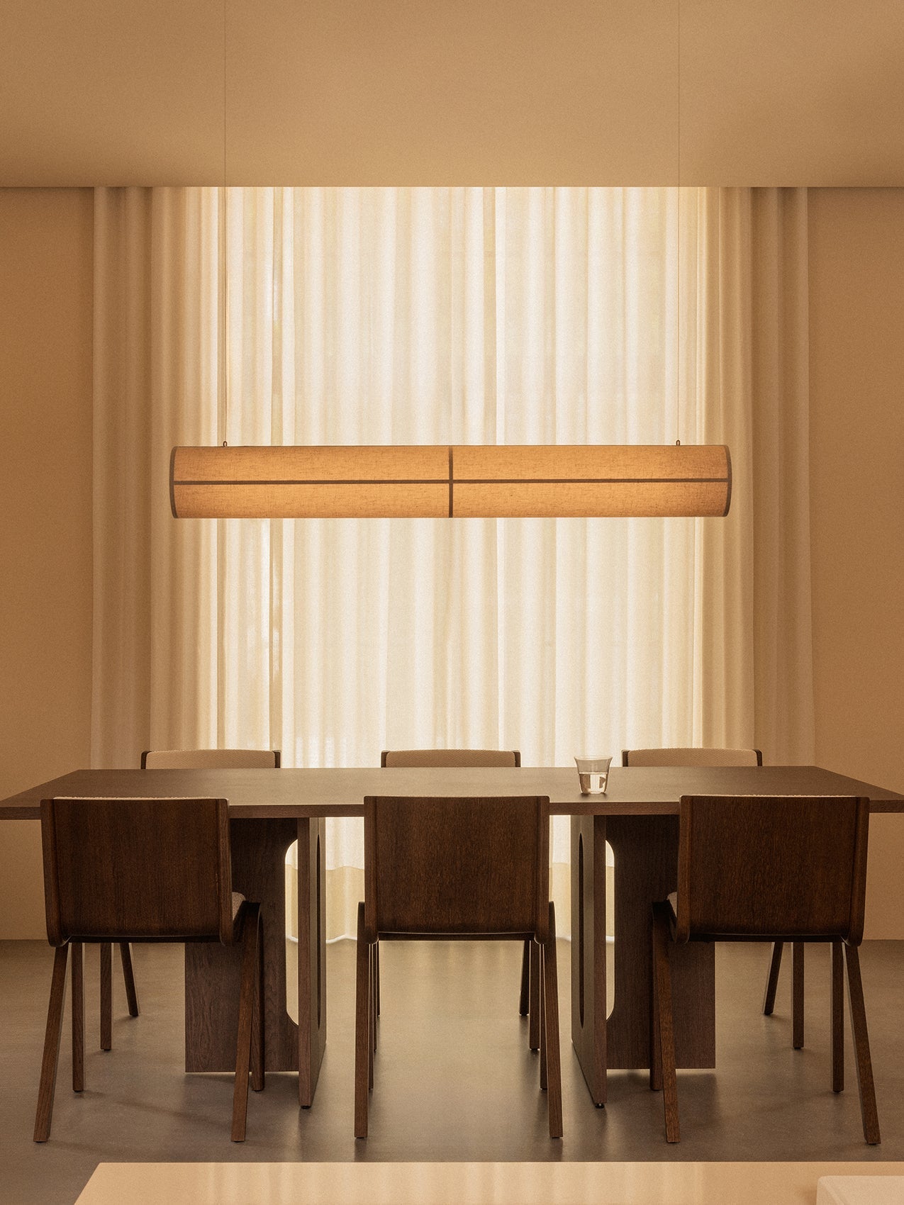 A dark wood Androgyne Dining Table and Ready Dining Chairs in a minimalist setting under a Hashira Linear Pendant Lamp.