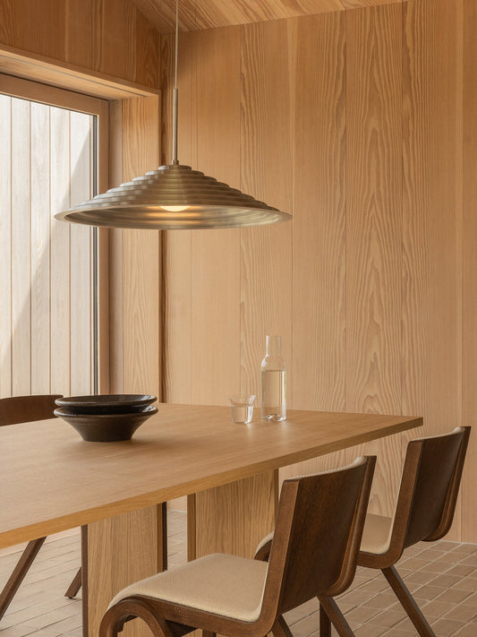 A wood-panelled dining room with a Chancery Pendant Lamp over an Androgyne Dining Table, Ready Chairs, and Triptych Bowls.