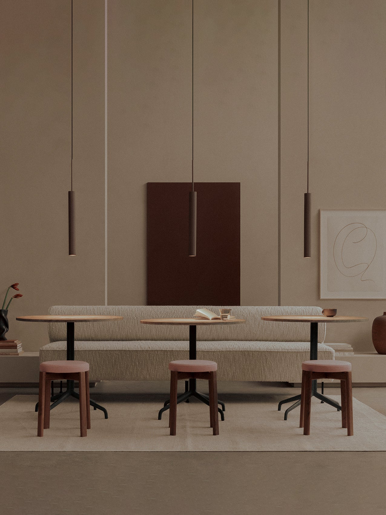 A long beige Eave Dining Banquette, set with Harbour Column Tables and pink Passage Stools under hanging Tubulaire Pendants