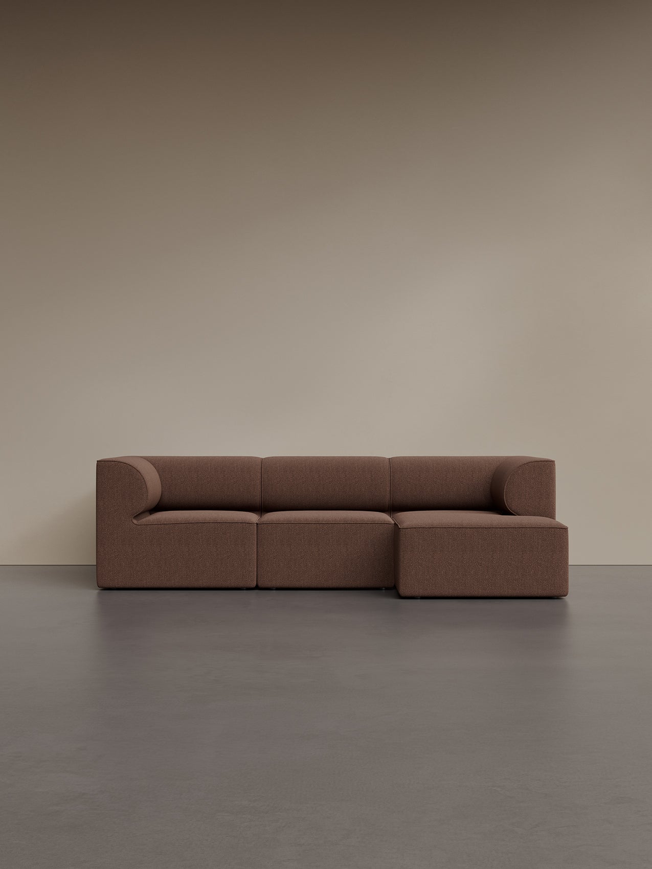 Eave Modular Sofa, a 3-seater with a right chaise longue in brown bouclé fabric, seen in a minimalist room with a grey floor.