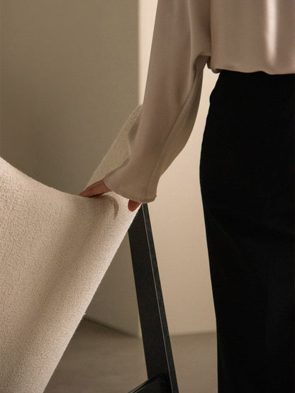 A person in a cream blouse touches the soft, ivory bouclé backrest of the Knitting Lounge Chair with a black oak frame.