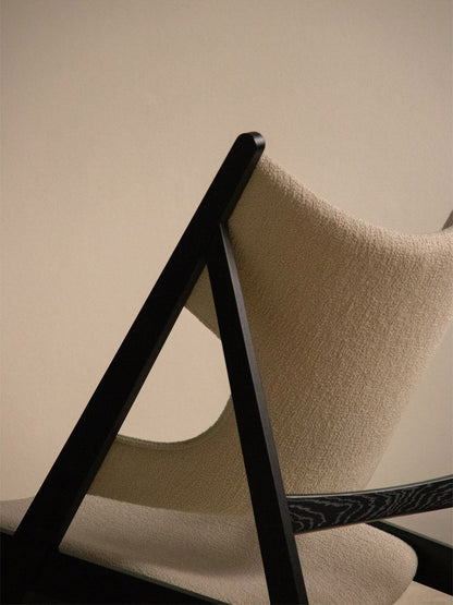 Close-up from behind the Knitting Lounge Chair, Black Oak, highlighting its black frame and textured ivory upholstery.