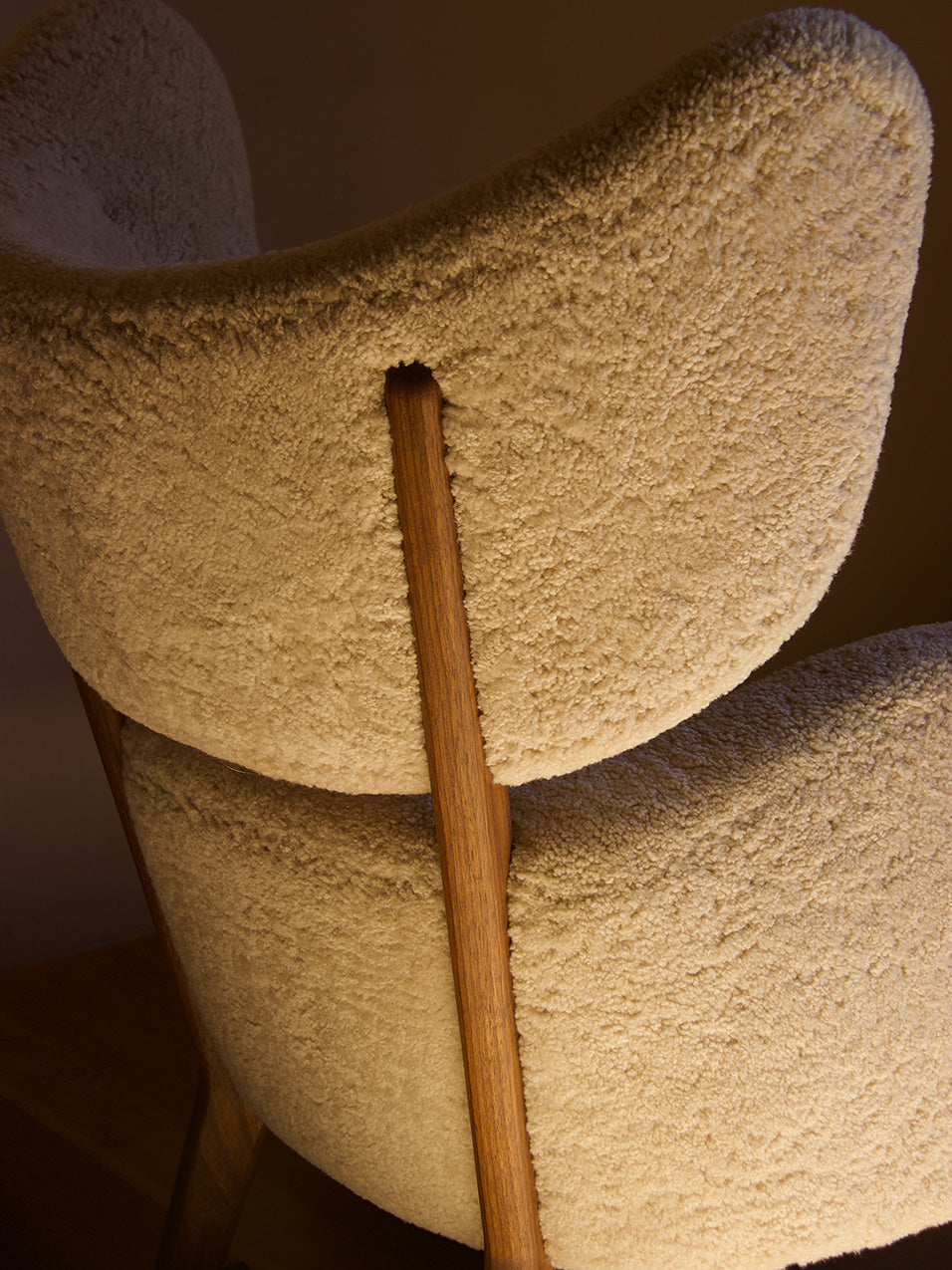 A close-up view of the back of the My Own Chair, showing the textural detail of the cream sheepskin and the wooden frame.