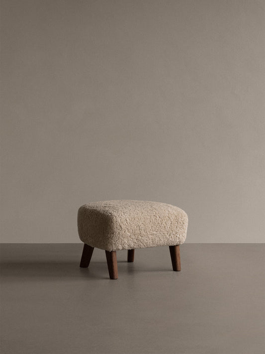 A My Own Chair, Ottoman, with a plush Sheepskin Moonlight seat and four dark wood legs, seen in a minimalist studio setting.