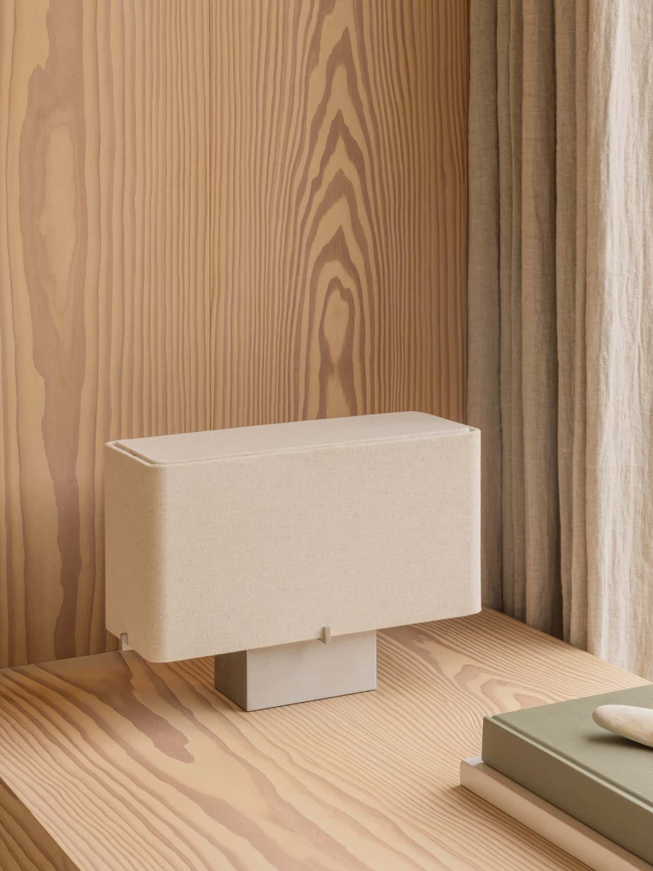 Nonna Table Lamp with a rectangular sand-coloured shade on a light wood desk against a matching wood-panelled wall.