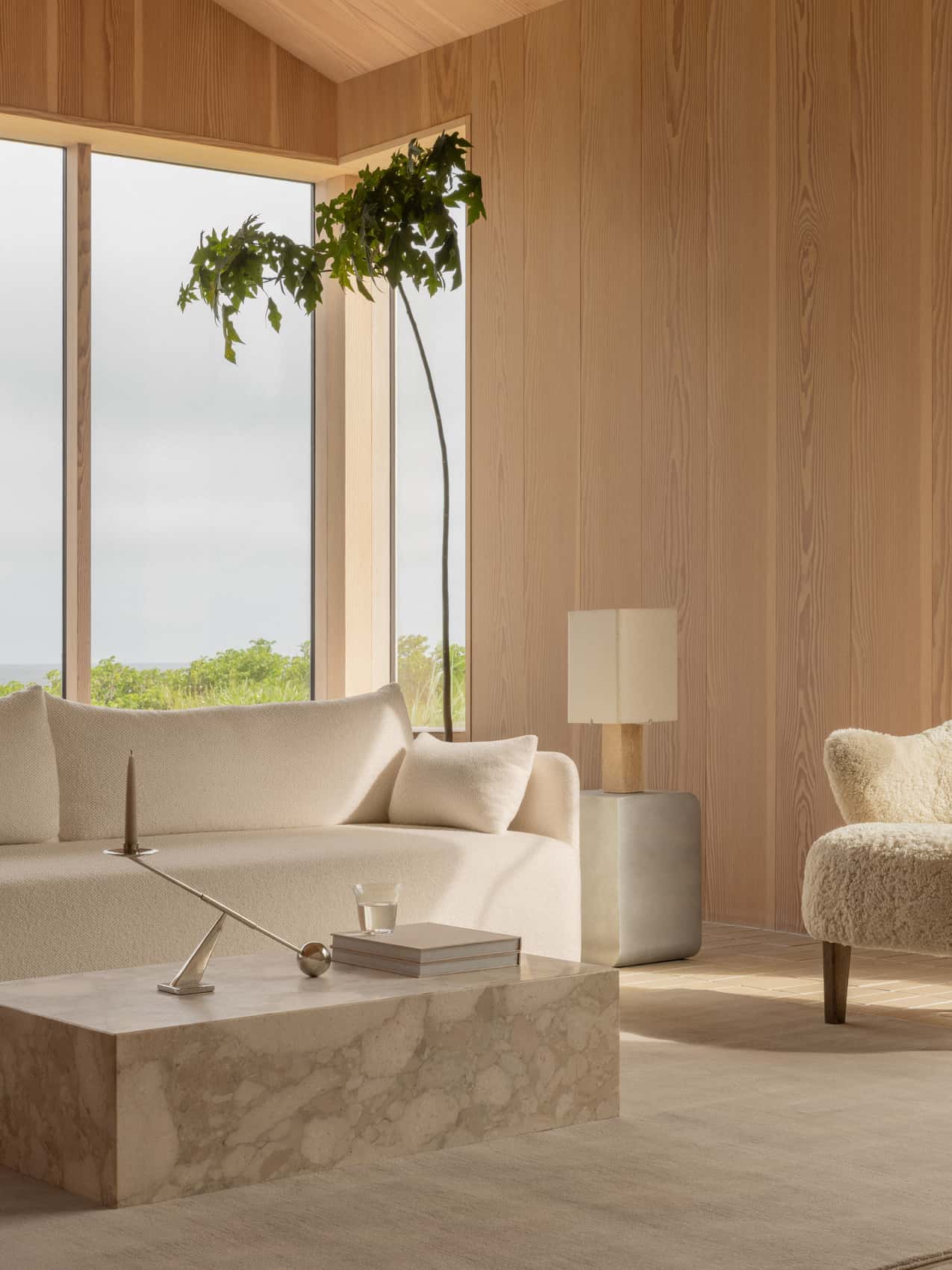 A tranquil, wood-panelled lounge with a Nonna Table Lamp, cream Offset Sofa, marble Plinth Low table and an Ingeborg chair.